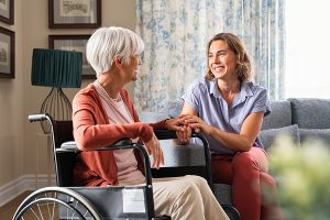 A caregiver talks with a senior in a wheelchair in a living room setting