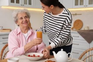 Caregiver serves breakfast to a senior at the kitchen table